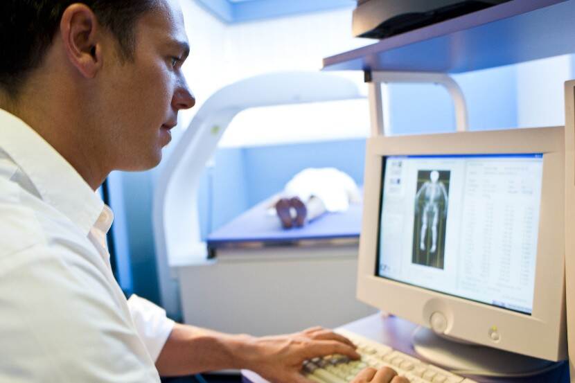 chiropractor achter beeldscherm met röntgenfoto om botdichtheid te meten